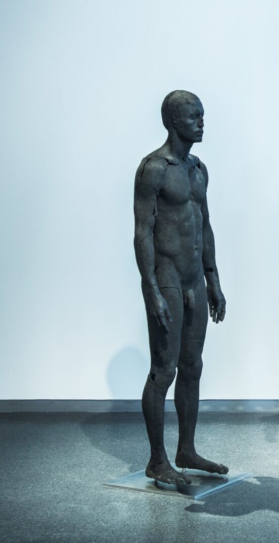 The Presence of Absence - Male : statue grandeur nature d'un homme nu et debout, réalisée par l'artiste britannique Tom Price à partir de charbon et de résine époxy, inspirée par les corps pétrifiés des victimes du Vésuve découverts à Pompéi.